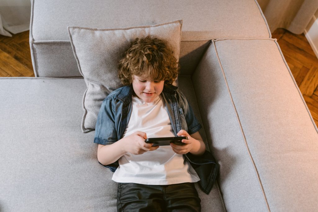 menino olhando para a tela do celular jogando jogos de bichinhos virtuais